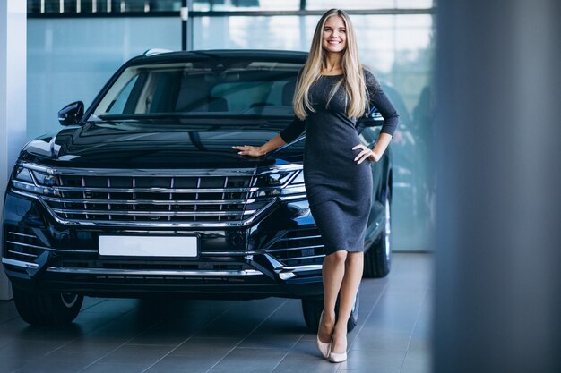 Mujer joven que elige un coche en un showroom de automóviles