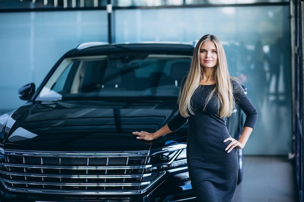 Mujer joven que elige un coche en un showroom de automóviles