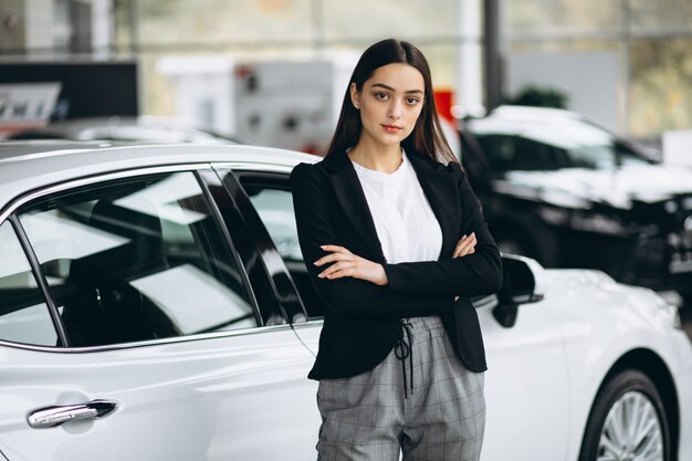 Mujer joven que elige un coche en un showroom de automóviles