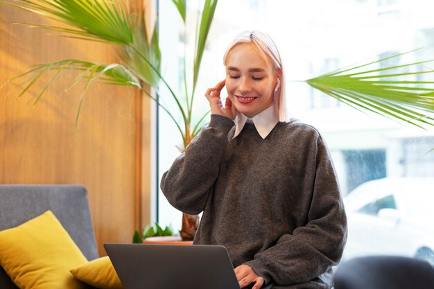 Mujer joven que estudia en una biblioteca mientras usa una computadora portátil