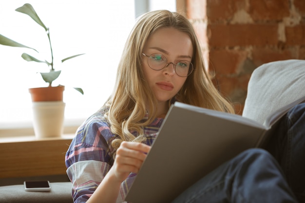 Mujer joven que estudia en casa durante cursos en línea o información gratuita sola