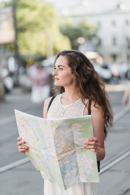 Mujer joven que explora la ciudad con el mapa