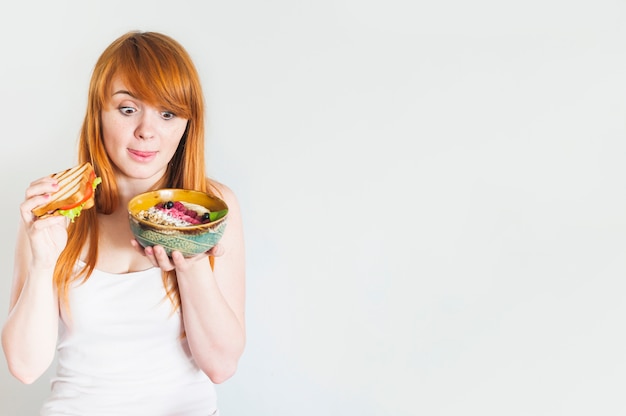 Mujer joven que se lame la lengua mientras mira el tazón de avena