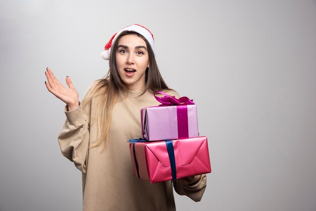 Mujer joven que lleva dos cajas de regalos de Navidad.