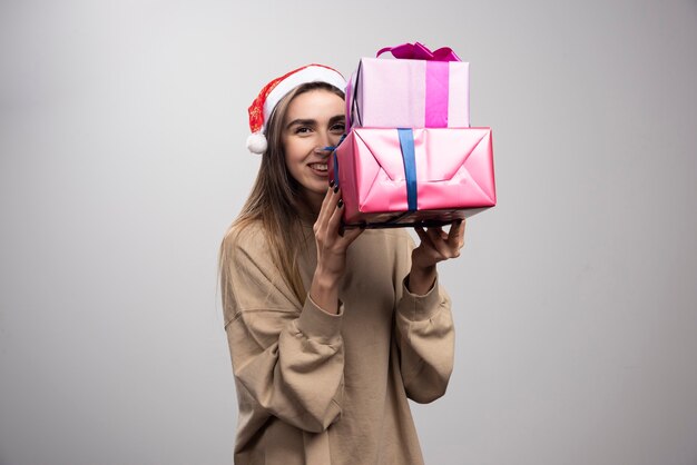 Mujer joven que lleva dos cajas de regalos de Navidad.