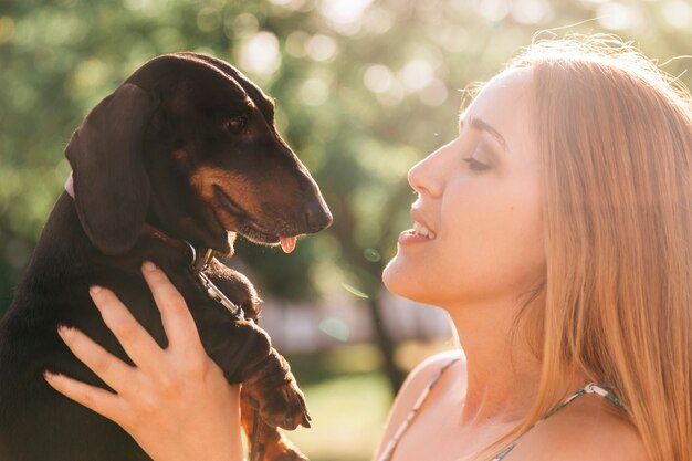 Mujer joven que lleva a su perro a la luz del sol