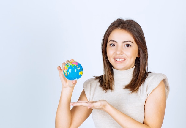 Mujer joven que muestra en una bola del globo terráqueo.