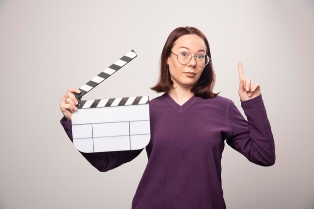 Mujer joven que muestra una cinta de cine sobre un fondo blanco. Foto de alta calidad