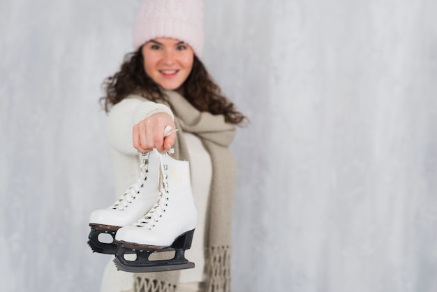 Foto gratuita mujer joven que muestra patines de hielo