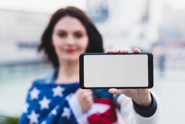 Mujer joven que muestra smartphone con pantalla en blanco