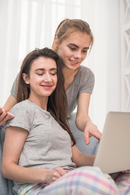 Mujer joven que muestra a su novia algo en la computadora portátil