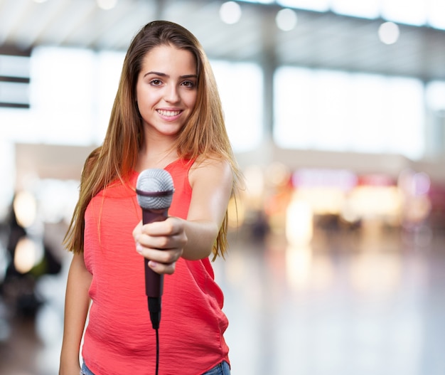 mujer joven que ofrece un micrófono en el fondo blanco