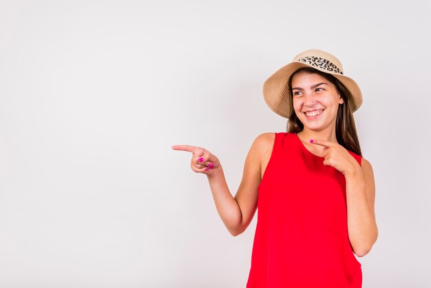 Mujer joven que presenta y que señala lejos en el fondo blanco