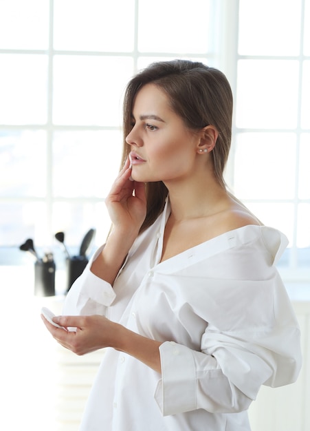 Mujer joven que quita maquillaje facial con toallitas desmaquillantes.