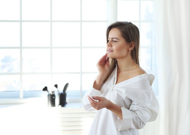 Mujer joven que quita maquillaje facial con toallitas desmaquillantes.