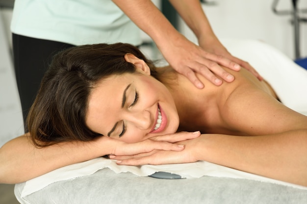 Mujer joven que recibe un relajante masaje de espalda en un centro de spa.