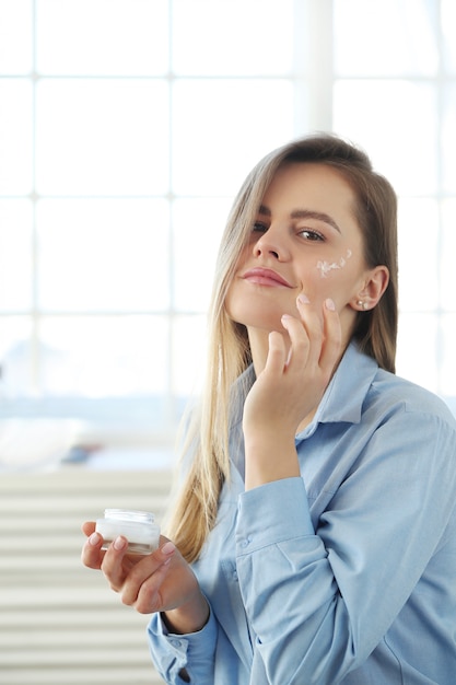 Mujer joven que se separa la crema facial. Concepto de cuidado de la piel.