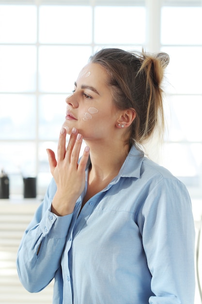 Mujer joven que se separa la crema facial. Concepto de cuidado de la piel.