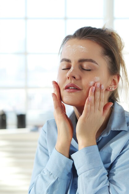 Mujer joven que se separa la crema facial. Concepto de cuidado de la piel.