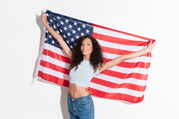 Mujer joven que sostiene la bandera americana aislada