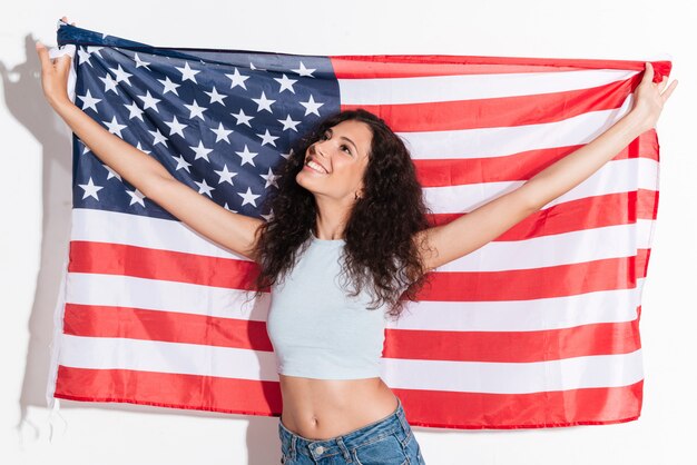 Mujer joven que sostiene la bandera americana aislada