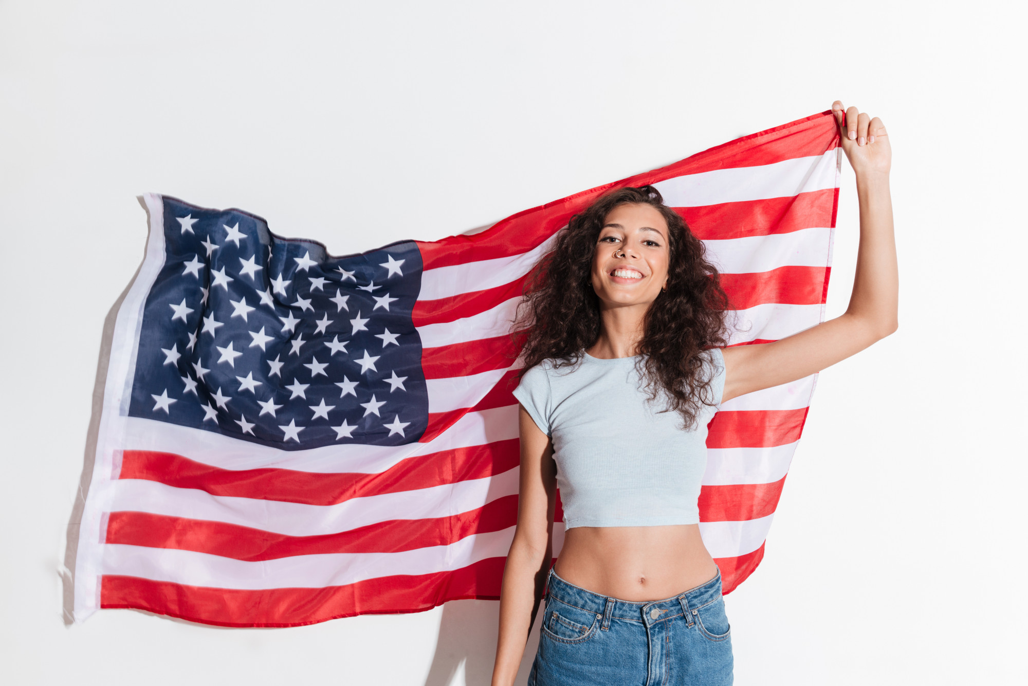 Mujer joven que sostiene la bandera americana aislada