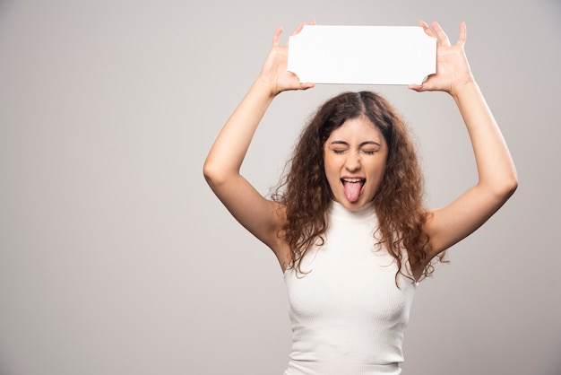 Mujer joven que sostiene el cartel vacío en blanco del discurso sobrecarga. Foto de alta calidad