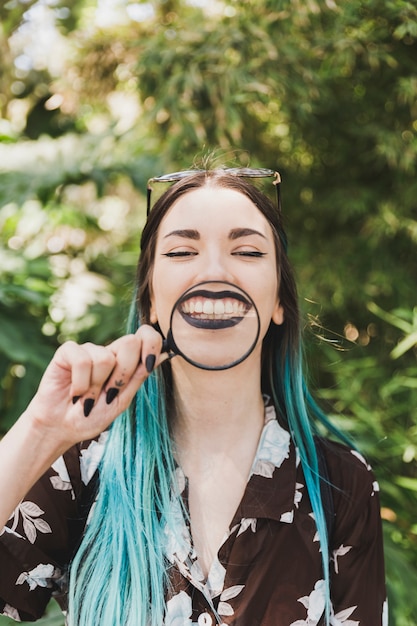 Foto gratuita mujer joven que sostiene la lupa sobre la sonrisa dentuda