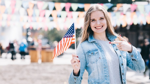 Mujer joven que sostiene la pequeña bandera de Estados Unidos