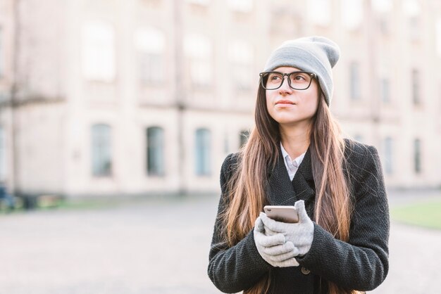 Mujer joven que sostiene smartphone en la calle