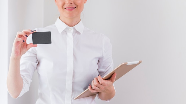 Mujer joven que sostiene la tableta digital que muestra la tarjeta de visita gris