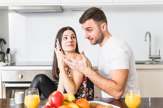 Mujer joven que sostiene el teléfono móvil que se sienta cerca de su novio