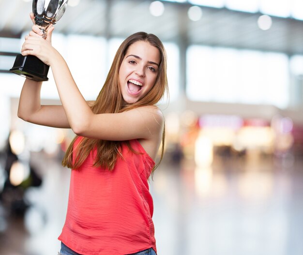 mujer joven que sostiene un trofeo en un fondo blanco