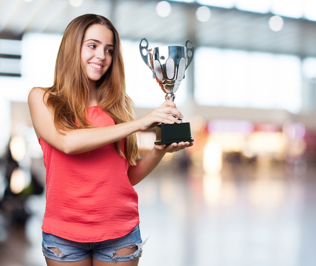 mujer joven que sostiene un trofeo en un fondo blanco