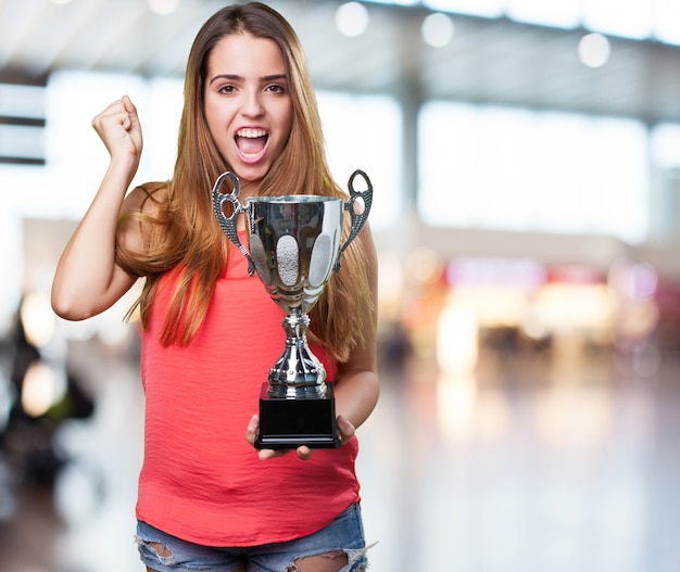 mujer joven que sostiene un trofeo en un fondo blanco