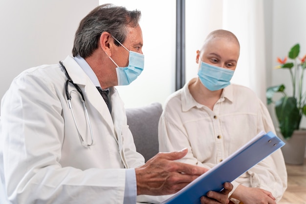 Foto gratuita mujer joven que sufre de cáncer de mama hablando con su médico