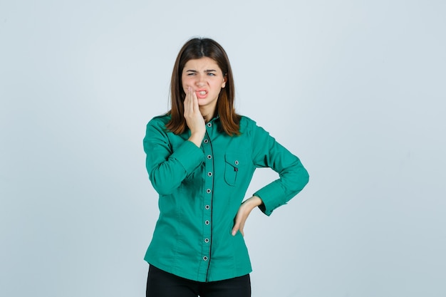 Foto gratuita mujer joven que sufre de dolor de muelas en camisa verde y parece doloroso. vista frontal.