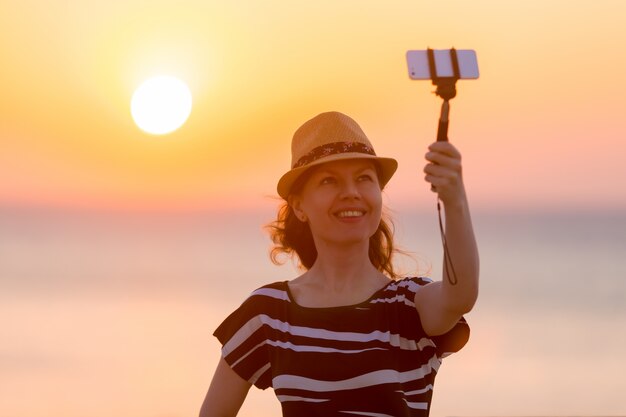 Mujer joven que toma la uno mismo-foto con la opinión del mar