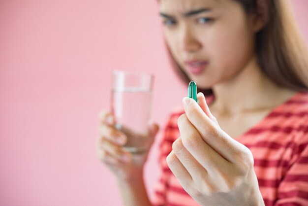 Mujer joven que toma la píldora de la medicina después de la orden del doctor