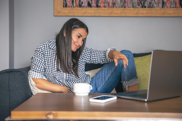 Foto gratuita una mujer joven que trabaja en una computadora portátil en casa