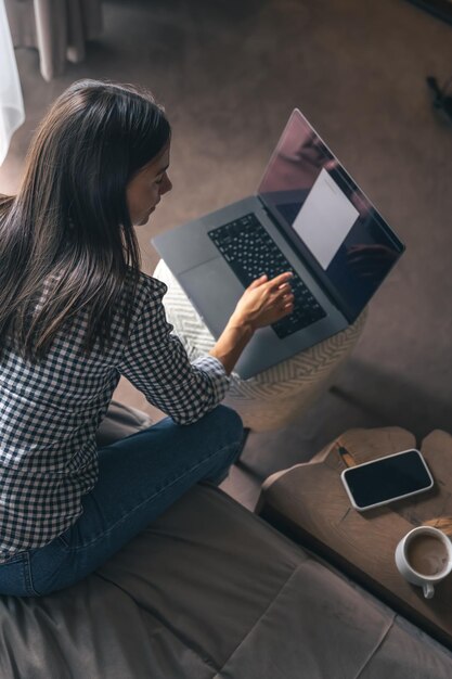 Una mujer joven que trabaja en una computadora portátil en casa