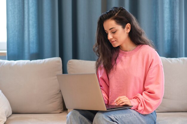 Mujer joven que trabaja en la computadora portátil en casa