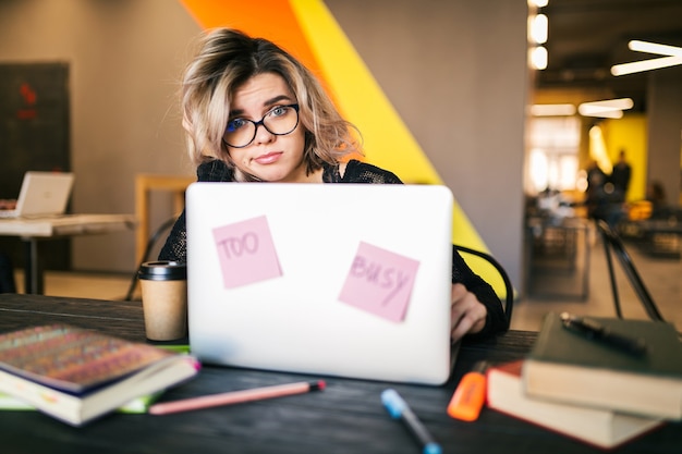 Foto gratuita mujer joven que trabaja en la computadora portátil en la oficina de trabajo conjunto