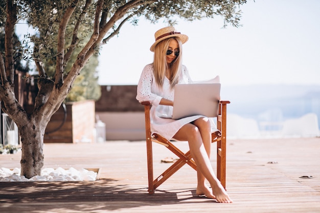 Mujer joven que trabaja en la computadora portátil en vacaciones