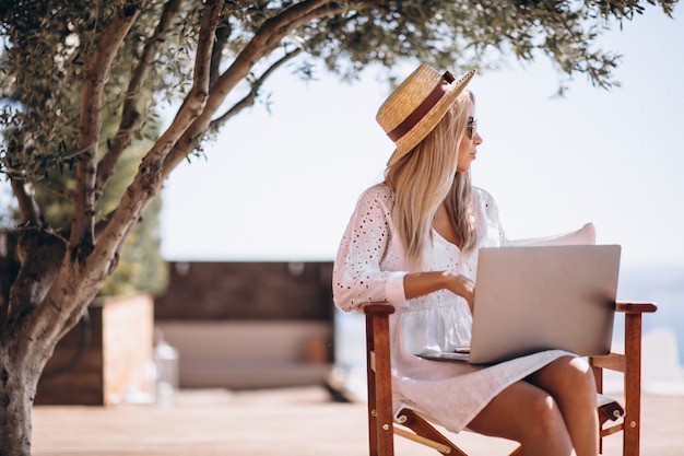 Mujer joven que trabaja en la computadora portátil en vacaciones