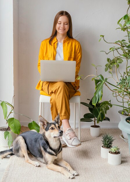 Foto gratuita mujer joven que trabaja en el jardín de su casa junto a su perro