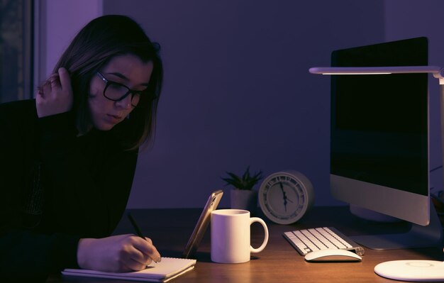 Una mujer joven que trabaja de noche en el lugar de trabajo.