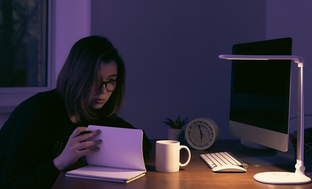 Una mujer joven que trabaja de noche en el lugar de trabajo.