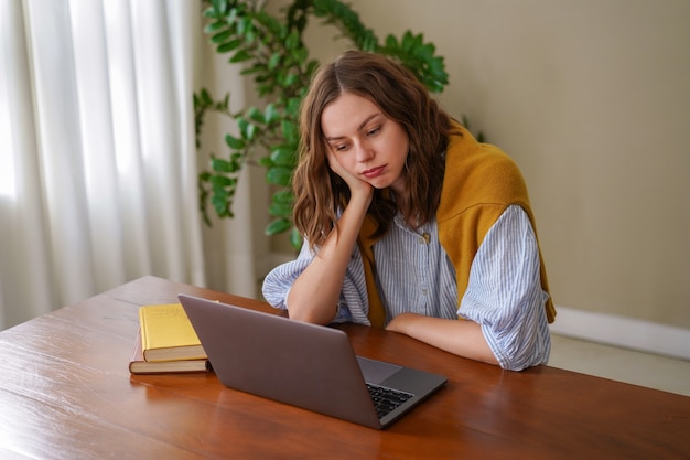 Mujer joven que trabaja en la oficina en casa independiente se siente cansado después del trabajo