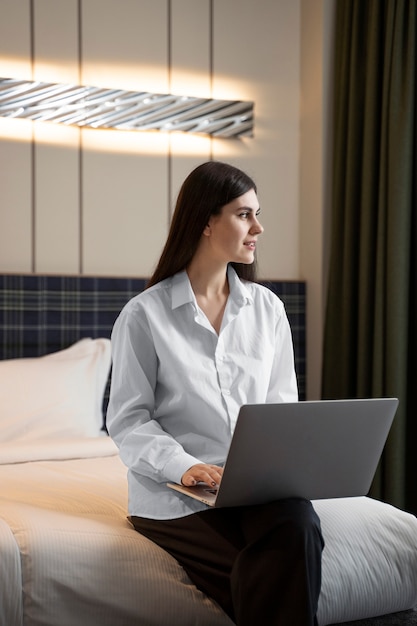 Mujer joven que trabaja en su computadora portátil en una habitación de hotel